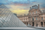 The Louvre Museum in Paris with its glass pyramid in the foreground and ornate building in the backg