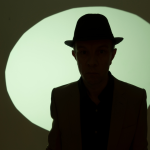 Mans shadow with hat over green backlit background