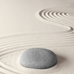 A photograph of an oval gray rock in sand.