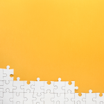 white puzzle pieces on an orange background.