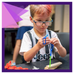 a child with dyed pink hair starts a build with small gears, links, and wooden blocks