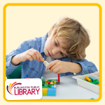 a white boy sits at a table building with multi-color Legos