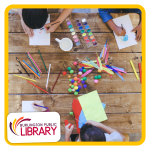 a top down photo of three kids working at a table with a variety of art supplies, including colored 
