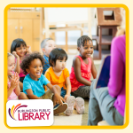 a group of preschoolers sits on a classroom rug while a teacher reads a story aloud to them