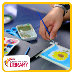 picture of a child's hand using blue paint, making a watercolor painting of a sunflower