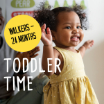 Toddler with medium brown skin, curly hair, and a yellow dress standing and smiling