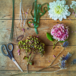 A table with flowers, scissors and other items for flower arranging.