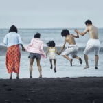 An image of the family jumping in the waves by the ocean from the movie,  "Shoplifters."