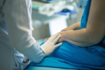 Image of a patient, and a healthcare professional gently putting hand on patient 