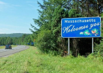A green space off the highway with a sign that says Massachusetts Welcomes You.