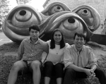 Three new Americans sitting together in front of a sculpture 