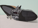 Cardboard puppet of a dragon's head painted black with white speckles.