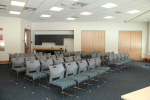 a bright room set up with a number of chairs facing the front of the room.