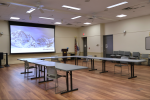 A large meeting room with a projector, set up with tables and chairs.