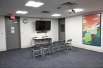 A small meeting room with chairs and a tv screen.