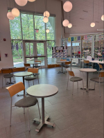 A large, brightly lit open space with tables and chairs in the center of the library.