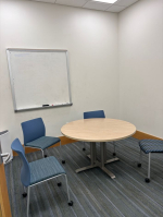 A small group study room with a table, chairs, and a whiteboard.