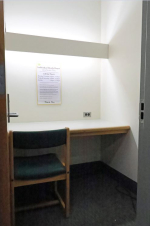 A small single person study room with one desk and chair against the wall.