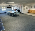 image of large carpeted meeting room with chairs,  tables, windows, counters