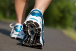 A pair of  feet with white and blue sneakers on them walking away from the viewer.
