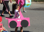 A little girl walks with a pink jeep made of cardboard around herself.