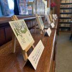 A book shelf with tiny canvases on tiny easels 