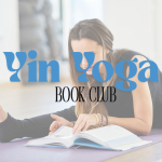 A young, smiling woman leans over her leg on a yoga mat, while reading a book
