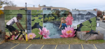 Mural on the side of a building in Haines Square. Children and a cyclist are interspered with large water lilies