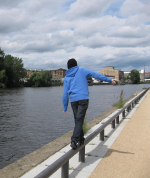 photo of preteen walking a fence along a river