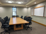 conference room with table, chairs, and whiteboard.