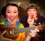  2 women in colorful clownish costumes with musical instruments.