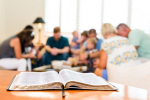 Open book with people meeting with folded hands.