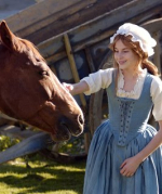 A girl in colonial clothing petting a horse.