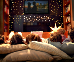 Children lying on pillows watching a movie.