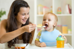 A babysitter feeding a toddler.