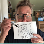 Rick Stomoski holding up one of his cartoons in front of his face.