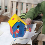 A child painting a birdhouse.
