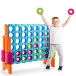 A boy standing next to a giant connect four game.