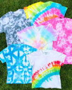 Several tie dye t-shirts in different colors pictured on a blanket.