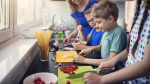 Kids chopping vegetables in a kitchen.