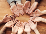 A circle of women's hands, all different skin tones.