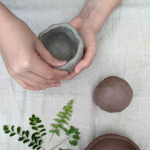 Hands making a clay pinch pot.