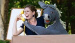 A woman holding a donkey puppet.