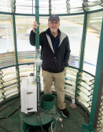 Jeremy D'Entremont standing inside the lens of a lighthouse