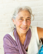A photo of a woman with grey hair smiling at the camera.