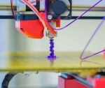 3D printer printing a purple spiral tower