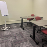 Office chairs and two tables with a white board in the room.