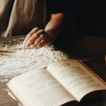 a cookbook open surrounded by flour.