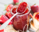 a jar of strawberry jam with a spoon in it.