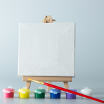 a blank canvas with paints and a paintbrush in front of it.